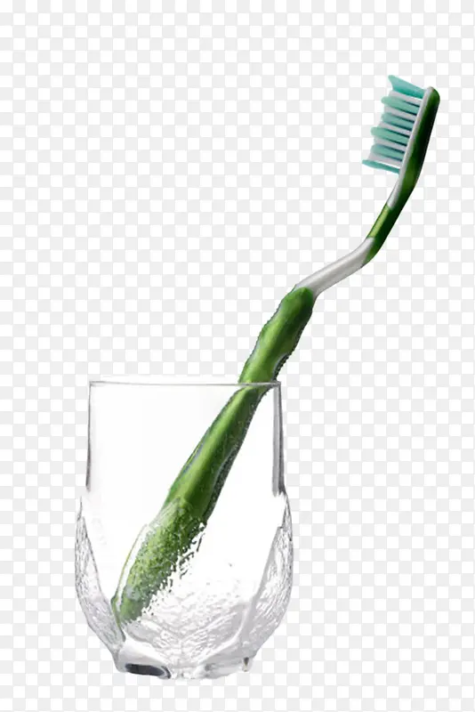 透明玻璃杯里的绿色牙刷实物